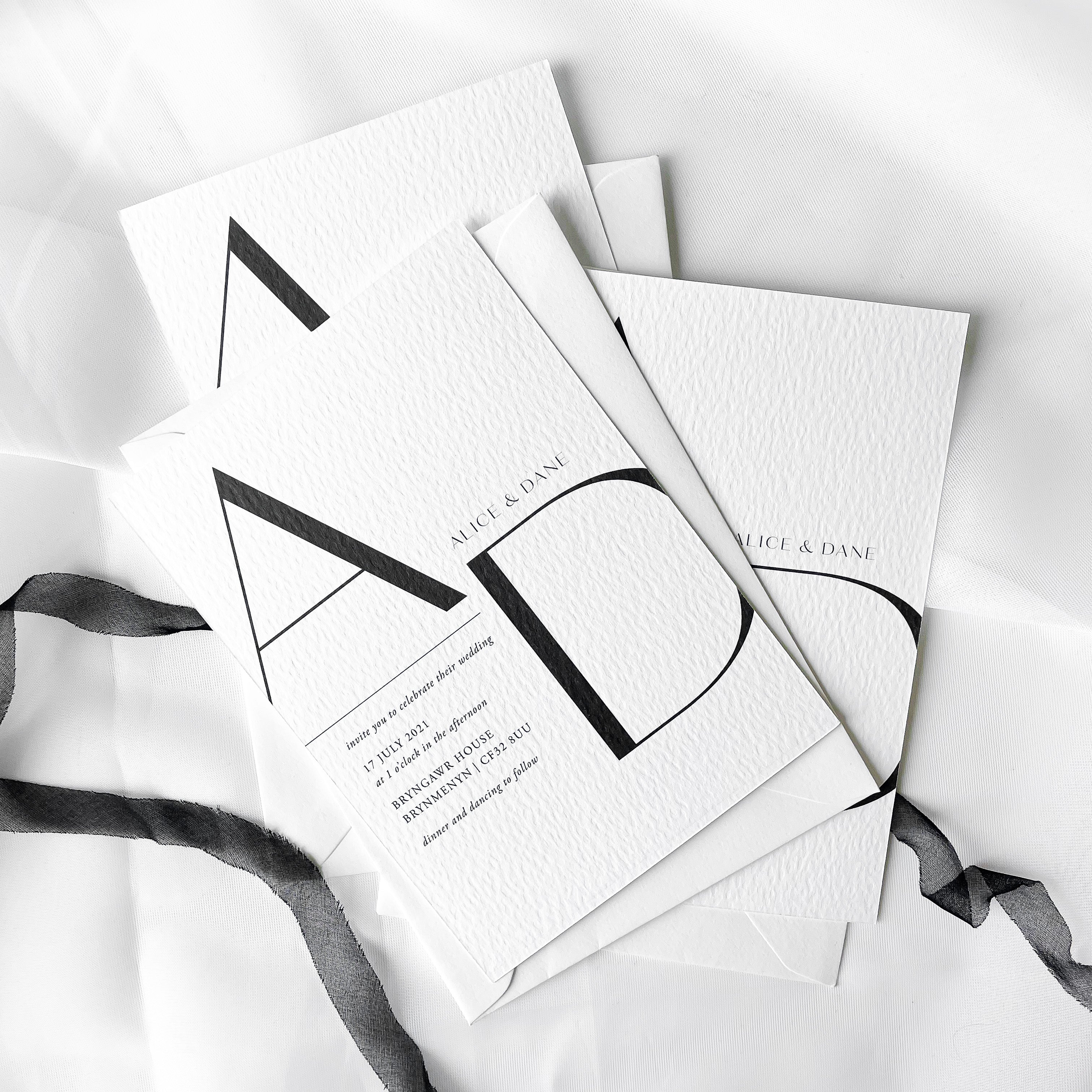 Minimalist monochrome wedding invitation suite with textured white card, elegant serif and script fonts, and premium finishes including hot foil, blind embossing and debossing styled for romantic garden weddings and modern elegant celebrations.